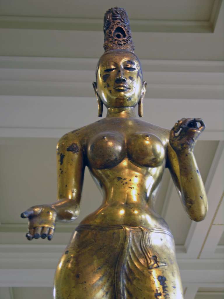 British Museum Top 20 06 Gilded Bronze Tara 6. Standing Tara  Sri Lanka, 8C AD, 143cm high. The statue of Tara, the consort of Avalokiteshvara, is solid cast in one piece of bronze and gilded. The goddess is naked to the waist with a lower garment flowing to her ankles. The marked contrast of the slender waist against heavy breasts and hips is the ideal of feminine beauty. Tara's right hand is shown in the mudra of giving; her left hand is empty but may have held a lotus flower.